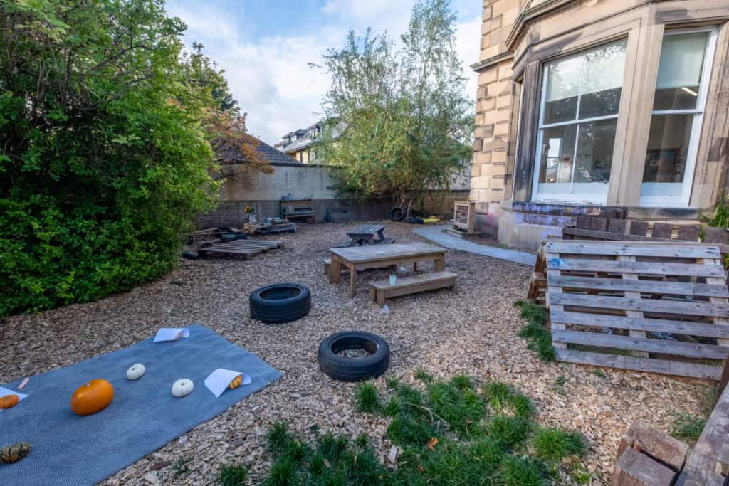 Bright outdoor play area at Thrive Childcare with natural grass and woodland surroundings, designed for children's learning and activities.