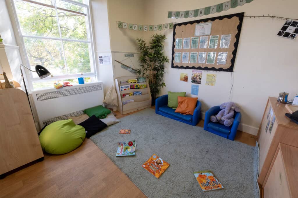 Bright, inviting childcare story corner with books, cushions, and educational posters at Thrive Childcare for children’s learning and relaxation.