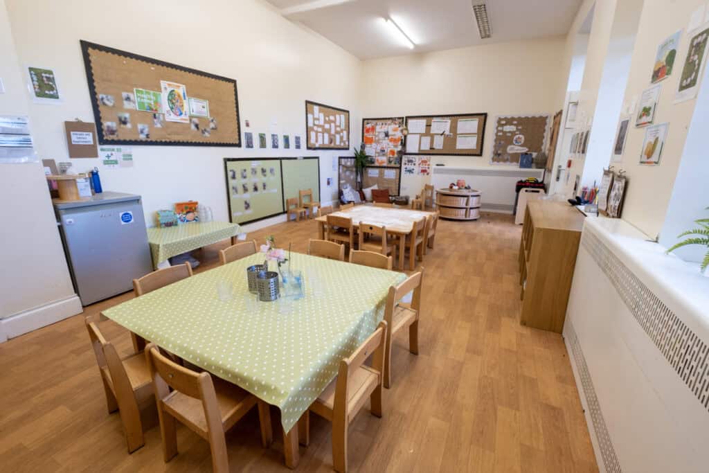 Bright indoor childcare room at Thrive Childcare with wooden furniture, educational displays, and colourful decorations, creating a safe and engaging environment for young children.