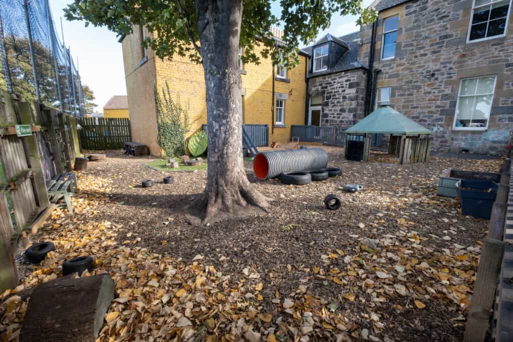 A colourful outdoor play area at Thrive Childcare with natural elements, climbing equipment, and shaded spaces, designed to support children's outdoor learning and play.