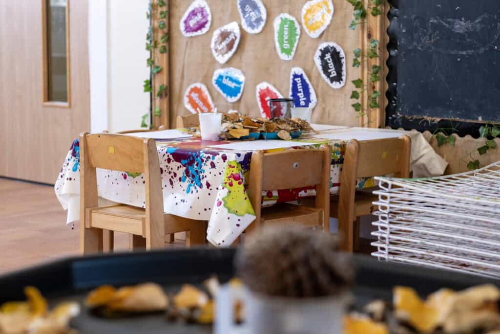 Colourful children's art classroom with a decorated table, craft materials, and wall displays promoting early childhood education and creative learning at Thrive Childcare.