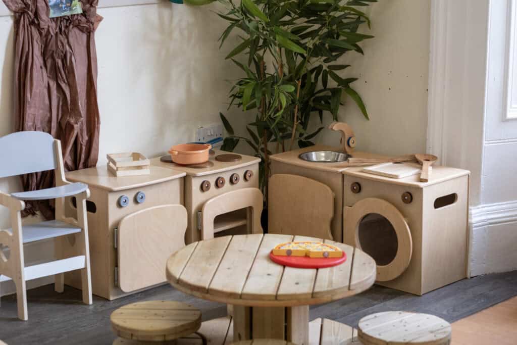 Wooden play kitchen set for children at Thrive Childcare, perfect for imaginative role play and fostering creativity in a caring early childhood environment.