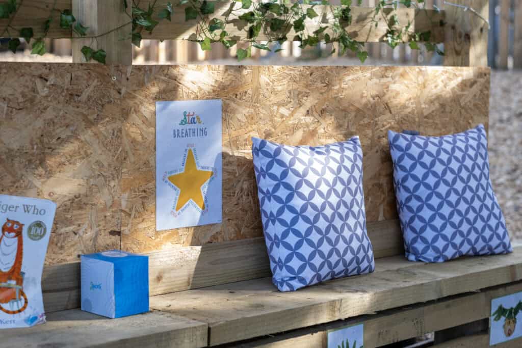 Bright outdoor play area at Thrive Childcare with cushions and educational posters, promoting relaxation and early childhood development in a safe, nurturing environment.