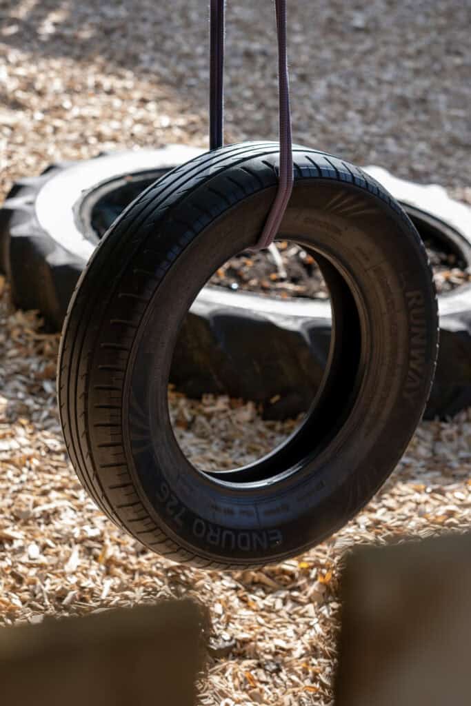 Bright and colourful outdoor playground tyre swing at Thrive Childcare, promoting fun, physical activity, and safe play for children in a nurturing childcare environment.