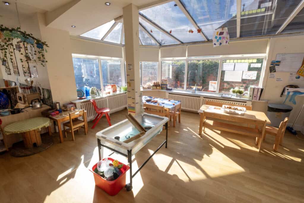 Bright and welcoming childcare classroom with natural sunlight, wooden furniture, and educational toys at Thrive Childcare for early childhood development and fun learning.