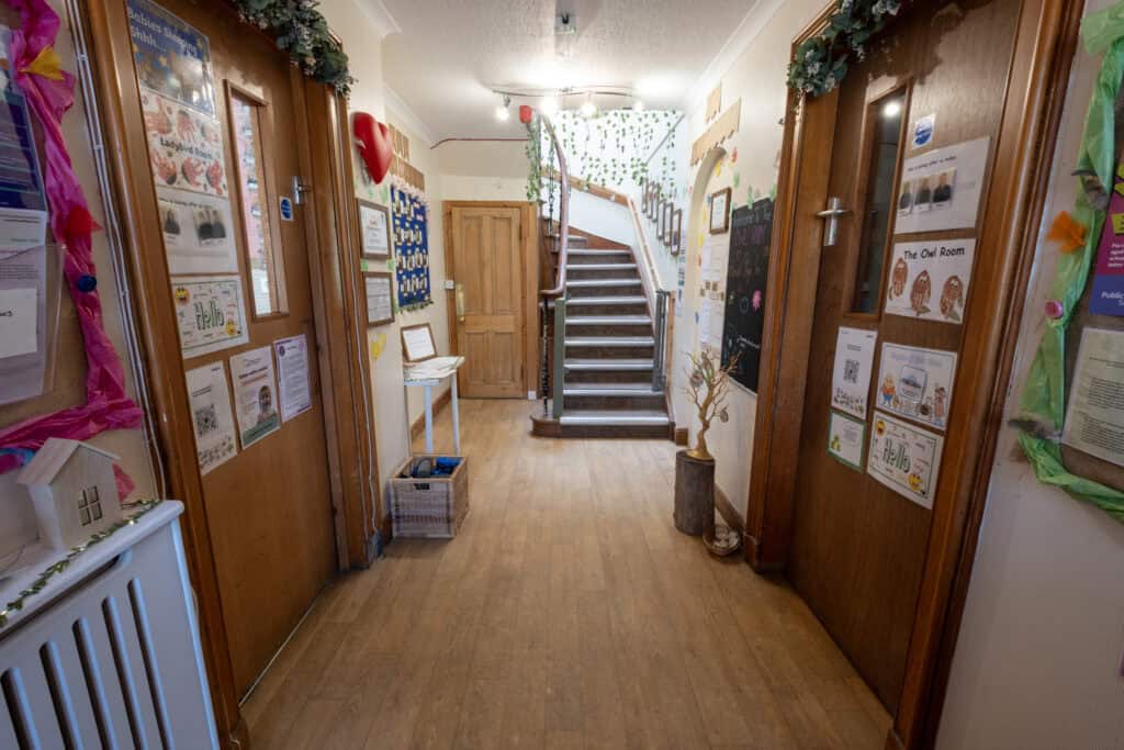 Bright indoor child care centre corridor with colourful artwork, notice boards, and wooden accents, ideal for fostering early childhood education and safe childcare services in a nurturing environment.