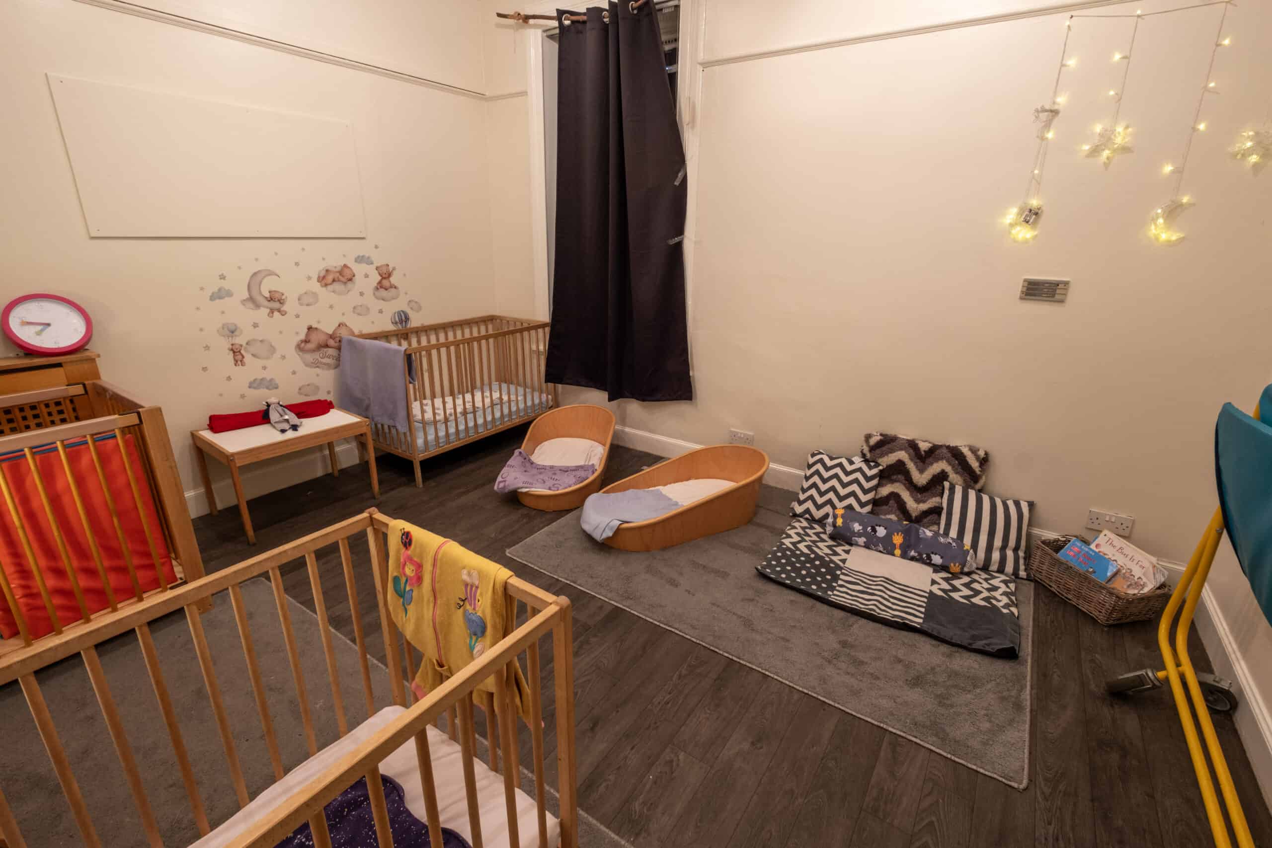 Soft playroom at Thrive Childcare featuring cribs, cozy bedding, toys, and nursery decor for infants and toddlers, creating a safe and nurturing environment for young children.