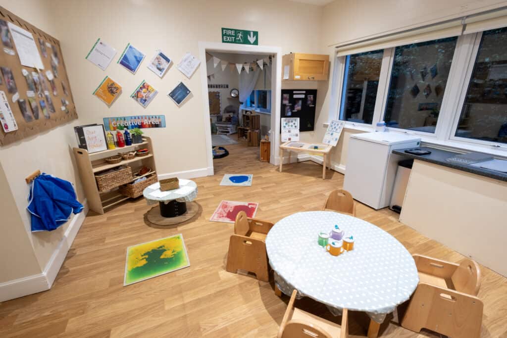 Bright indoor childcare playroom at Thrive Childcare featuring creative arts area, toddler table, and educational toys, designed to promote learning and development in a safe, inviting environment.