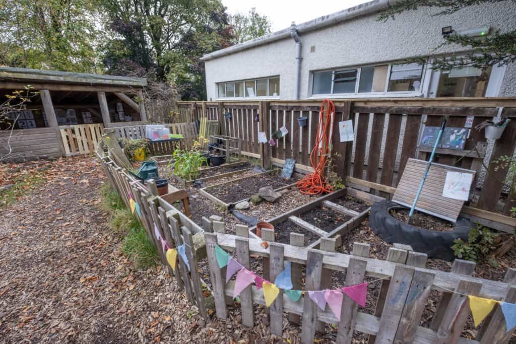Colourful outdoor garden at Thrive Childcare with vegetable patches, gardening tools, and children's artwork, creating a safe and engaging environment for early childhood development.