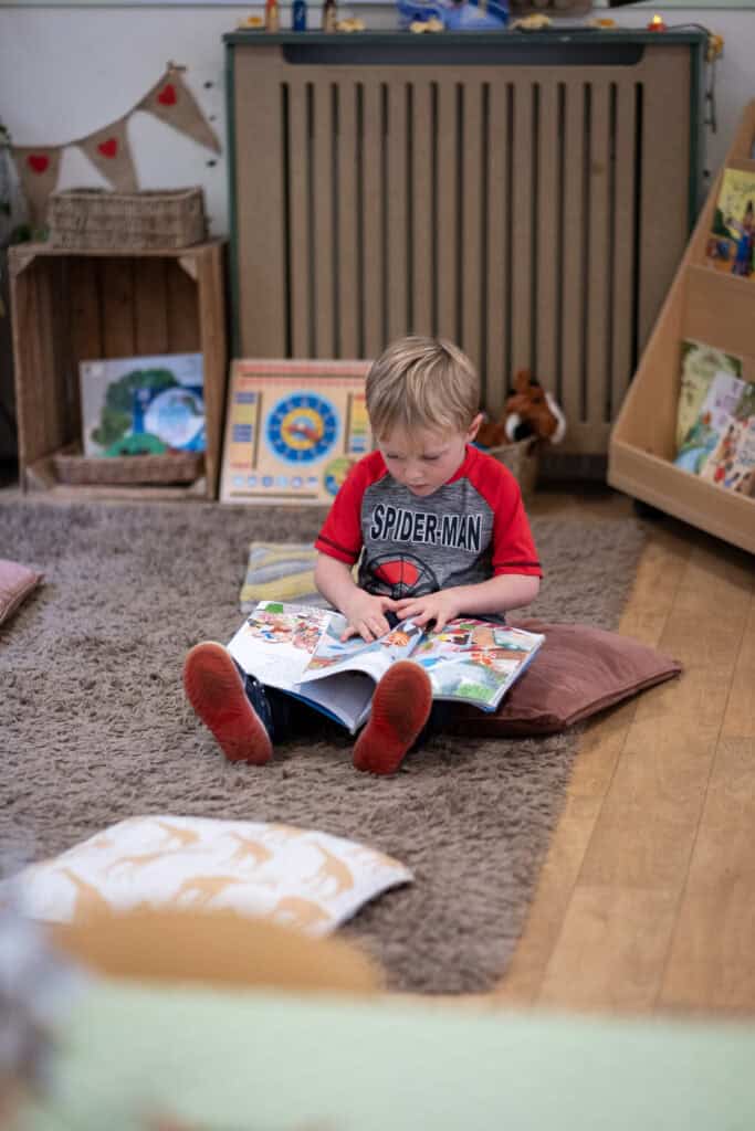 Child reading picture book in a welcoming childcare environment, fostering early literacy skills and cognitive development.