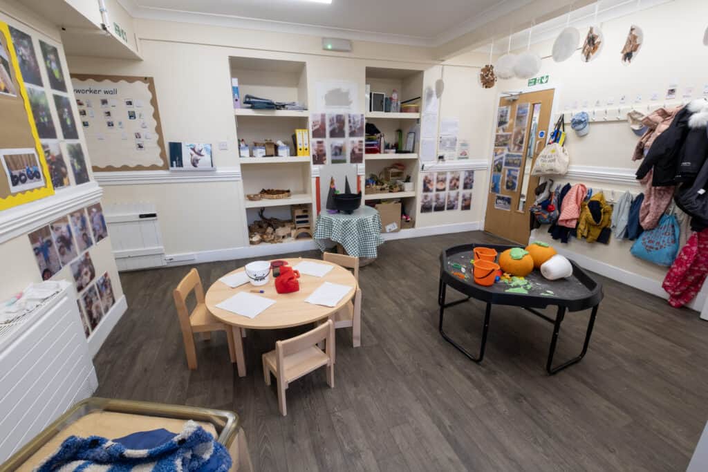 Bright indoor childcare room at Thrive Childcare with educational toys, coat hooks, and child-sized furniture, providing a safe and engaging environment for early childhood development.