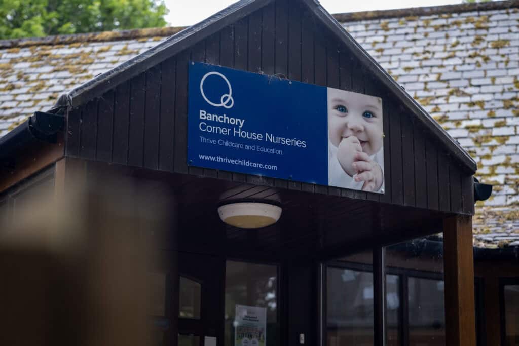 1. Bright blue sign at Banchory Corner House Nurseries with a smiling baby photo, promoting childcare and early education services in Banchory, Scotland.