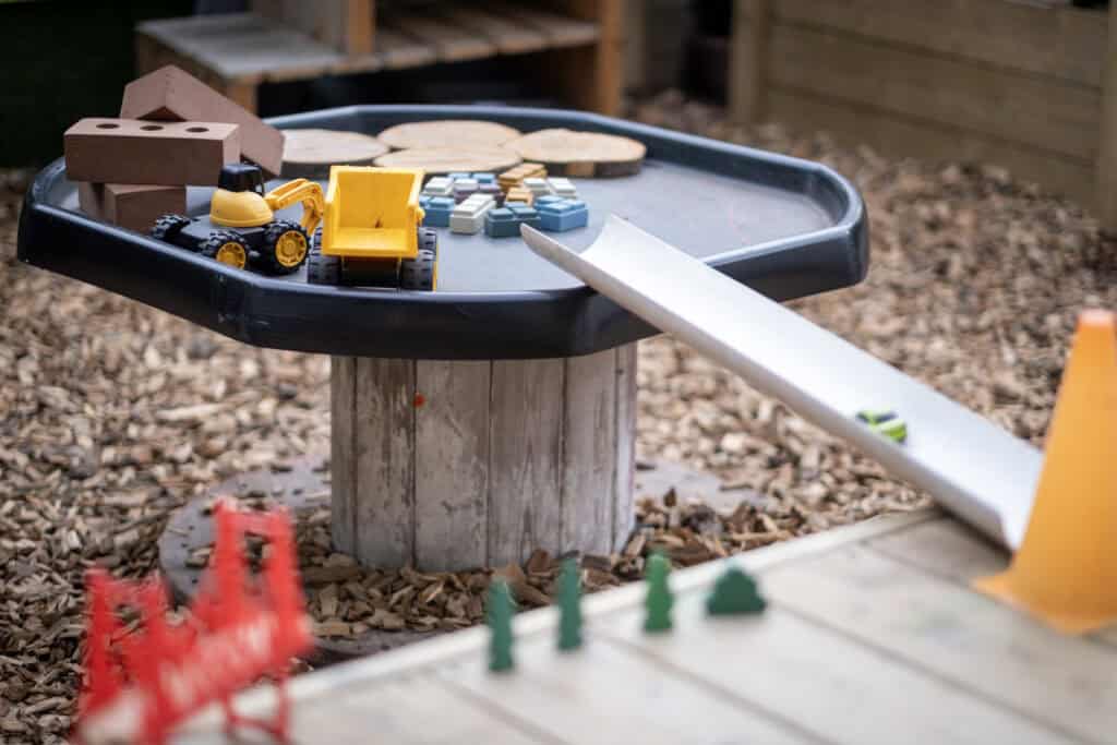 Bright outdoor play area with construction toys and wooden blocks at Thrive Childcare, fostering imaginative skills and active learning for children in a safe, engaging environment.