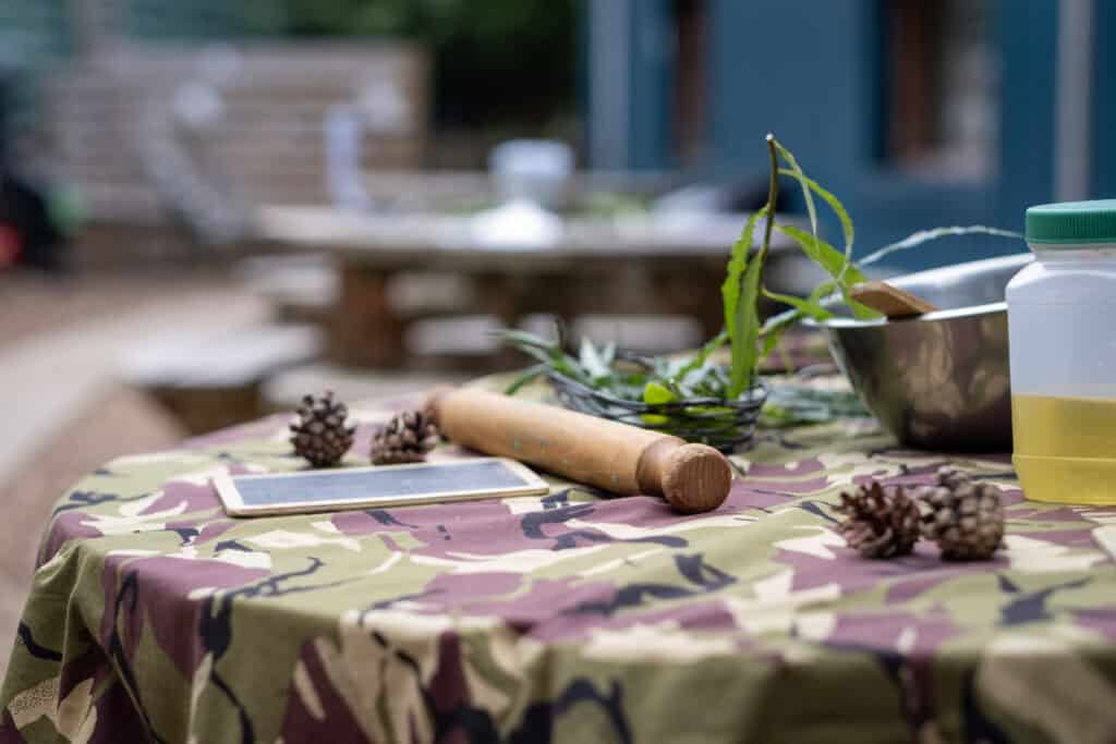 A colourful outdoor table setup at Thrive Childcare, featuring natural items and craft supplies, ideal for encouraging children’s creativity and outdoor learning activities.