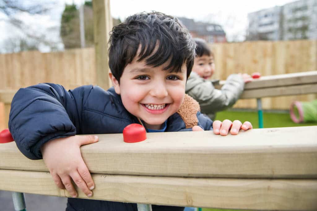 Happy young boy smiling outdoors at Thrive Childcare, enjoying outdoor play in a secure childcare environment in the UK.