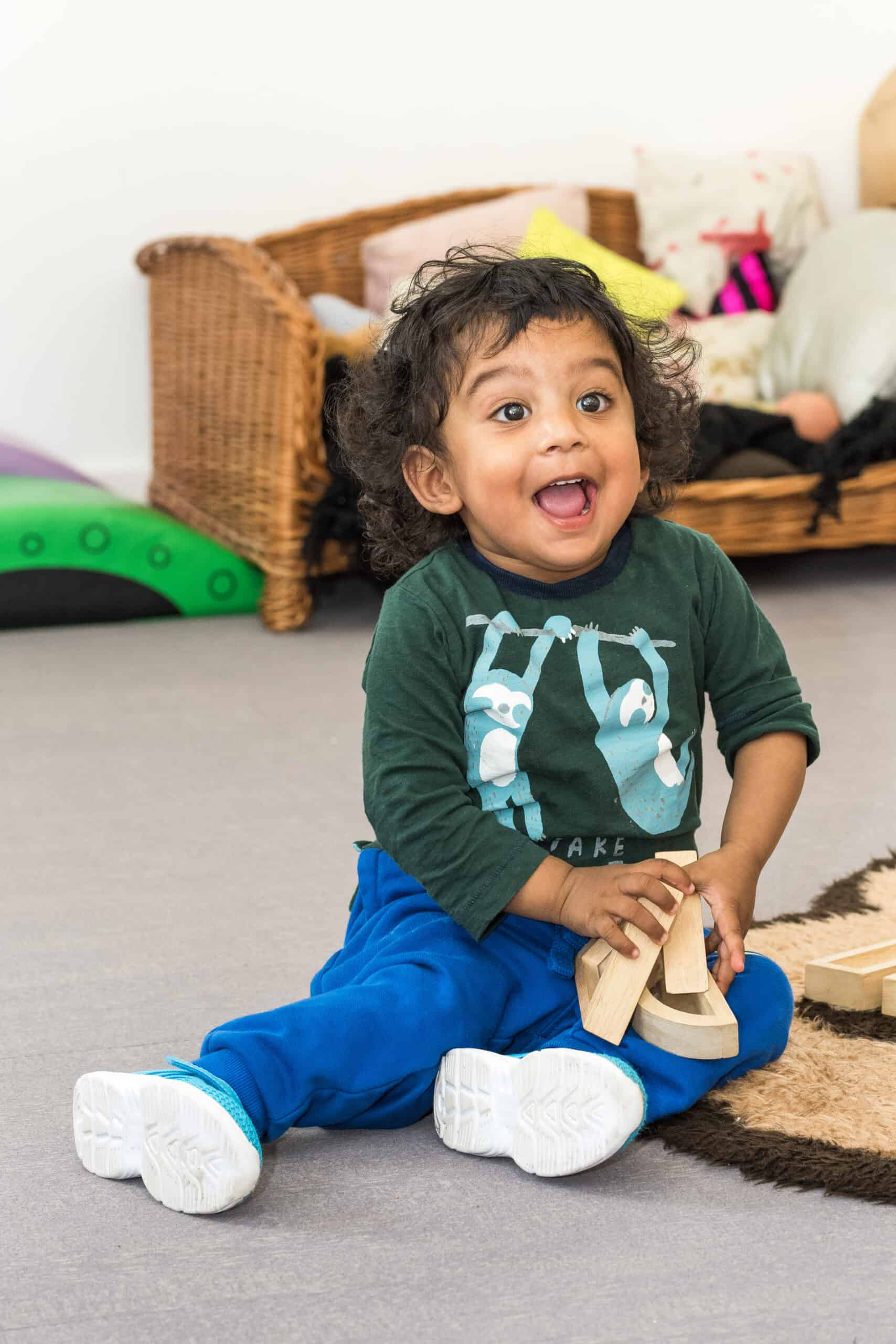 1. Adorable young child playing with wooden blocks in a colourful childcare centre at Thrive Childcare in the UK.