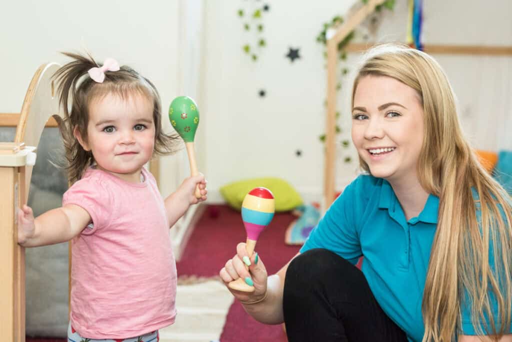 Bright young girl and childcare professional engaging in playful activities at Thrive Childcare centre in en_GB.