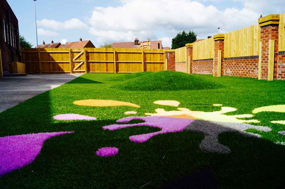 Colourful outdoor children's play area at Thrive Childcare with vibrant grass art and secure fencing, creating a safe and stimulating environment for early childhood development.