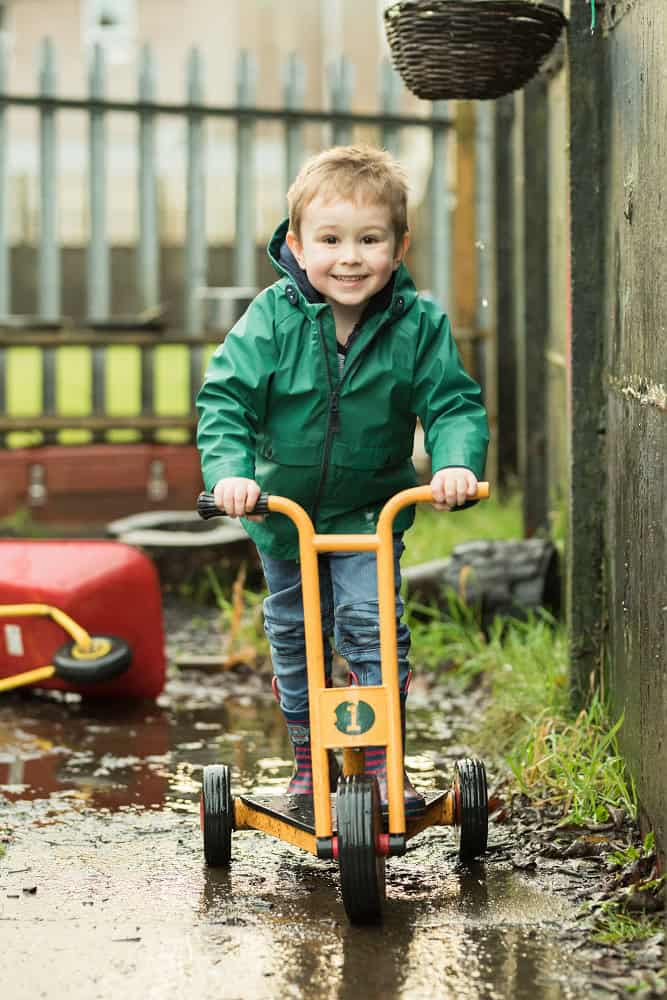 Young boy riding a tricycle in an outdoor play area at Thrive Childcare, highlighting safe outdoor activities for children.