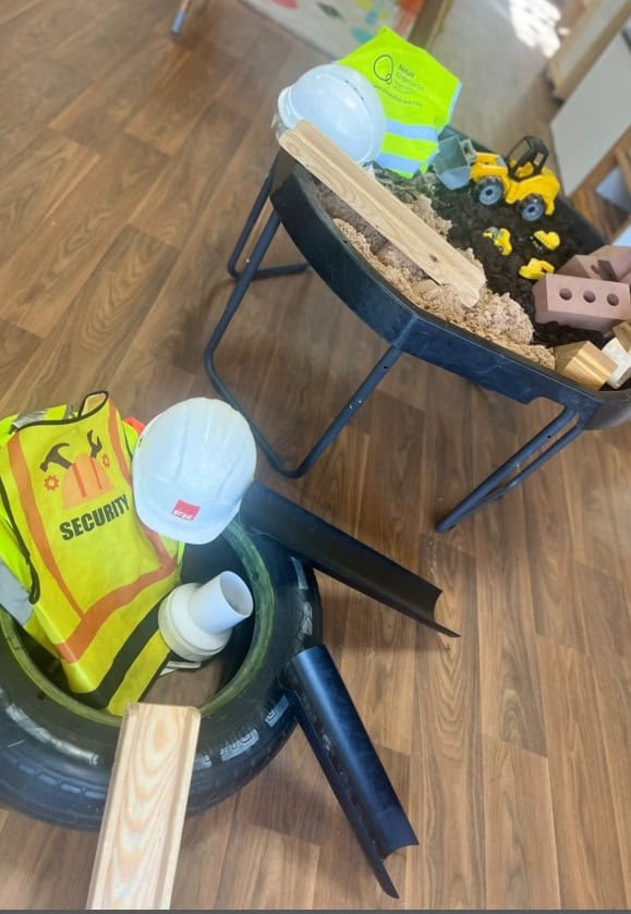 Security vest and construction toys on a toddler play table in a childcare setting.