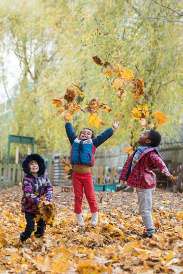 Children playing and enjoying autumn leaves at Thrive Childcare, a nurturing early years education and childcare centre.