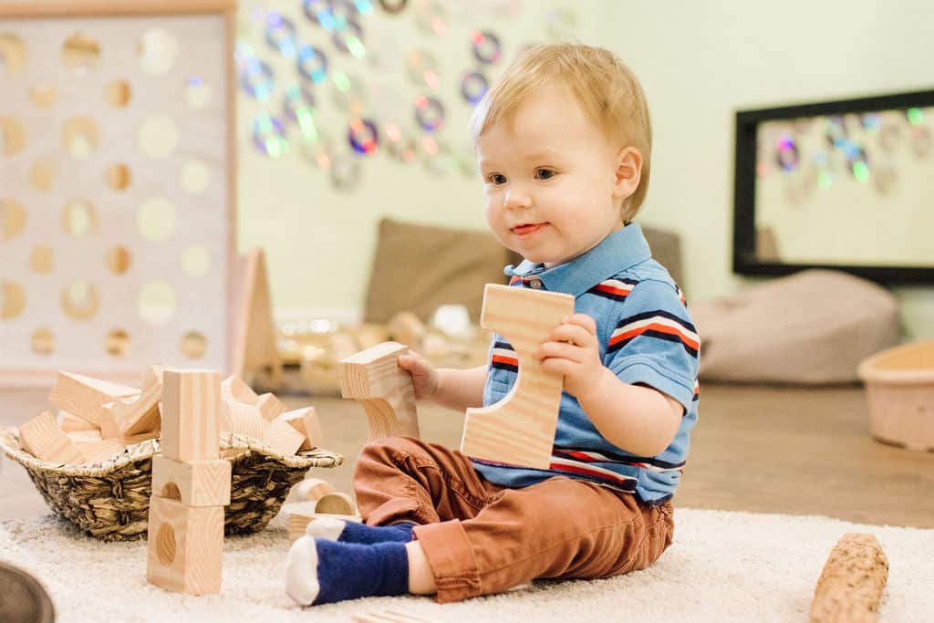 Elegant, natural light-filled nursery with young child playing with wooden blocks, promoting early childhood development and learning at Thrive Childcare in a safe, nurturing environment.