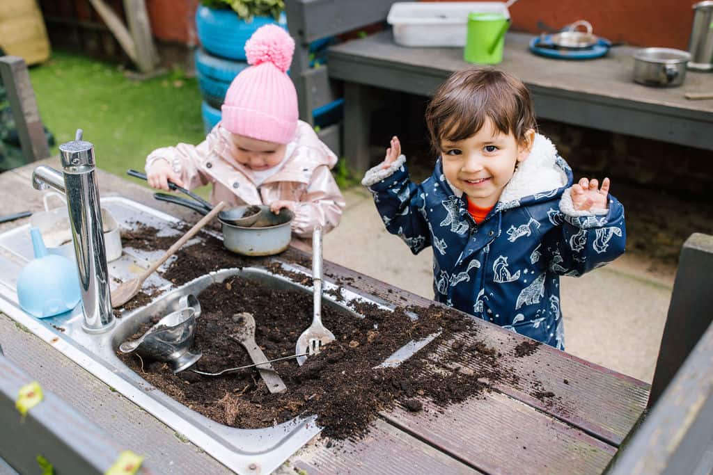 Childrens outdoor play activity at Thrive Childcare, exploring soil and gardening toys, promoting early learning and sensory development.