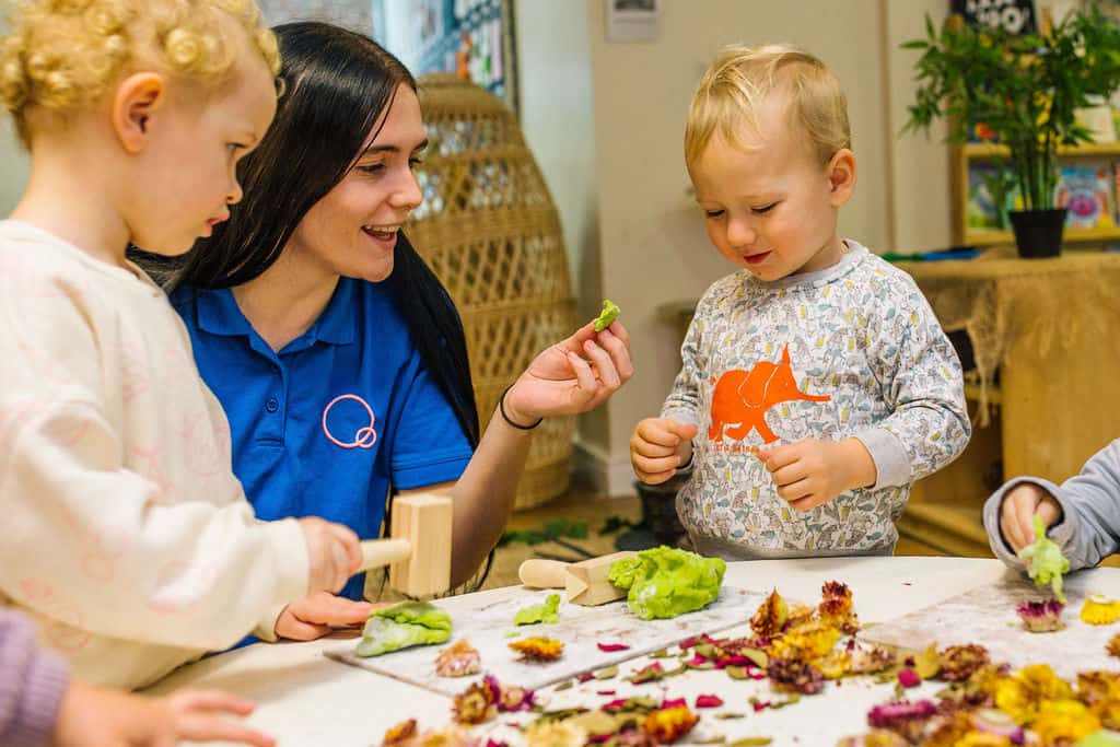 A cheerful childcare provider interacting with young children during a fun, educational activity at Thrive Childcare, promoting early childhood development and learning in a nurturing environment.