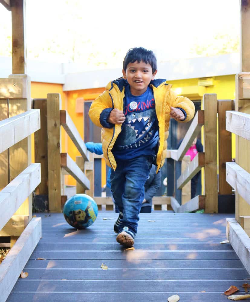 Happy young boy playing outside at Thrive Childcare, engaging in outdoor activities and sports, promoting active play, learning, and child development in a safe environment.