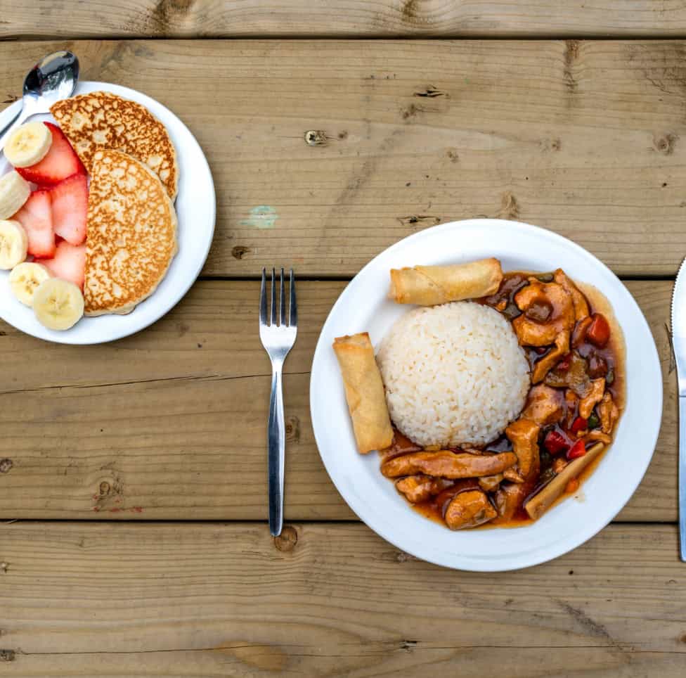 Freshly prepared children's meal with rice, stir-fried chicken and vegetables, spring rolls, and a side of pancake with fresh fruit for healthy eating and nutritional balance at Thrive Childcare.