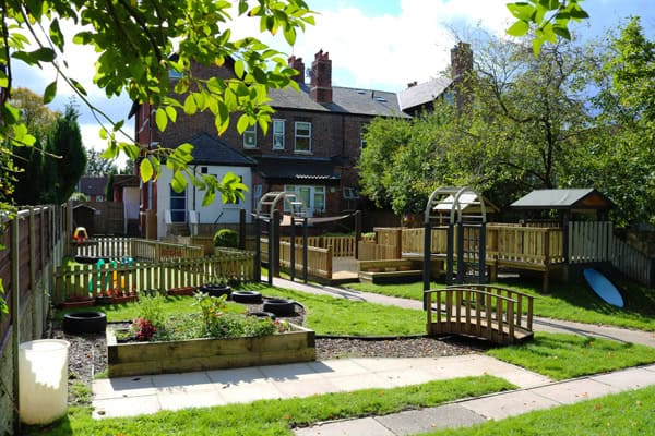 A safe and vibrant outdoor playground area at Thrive Childcare, featuring wooden play structures, greenery, and engaging activities for children to explore and develop in a nurturing environment.