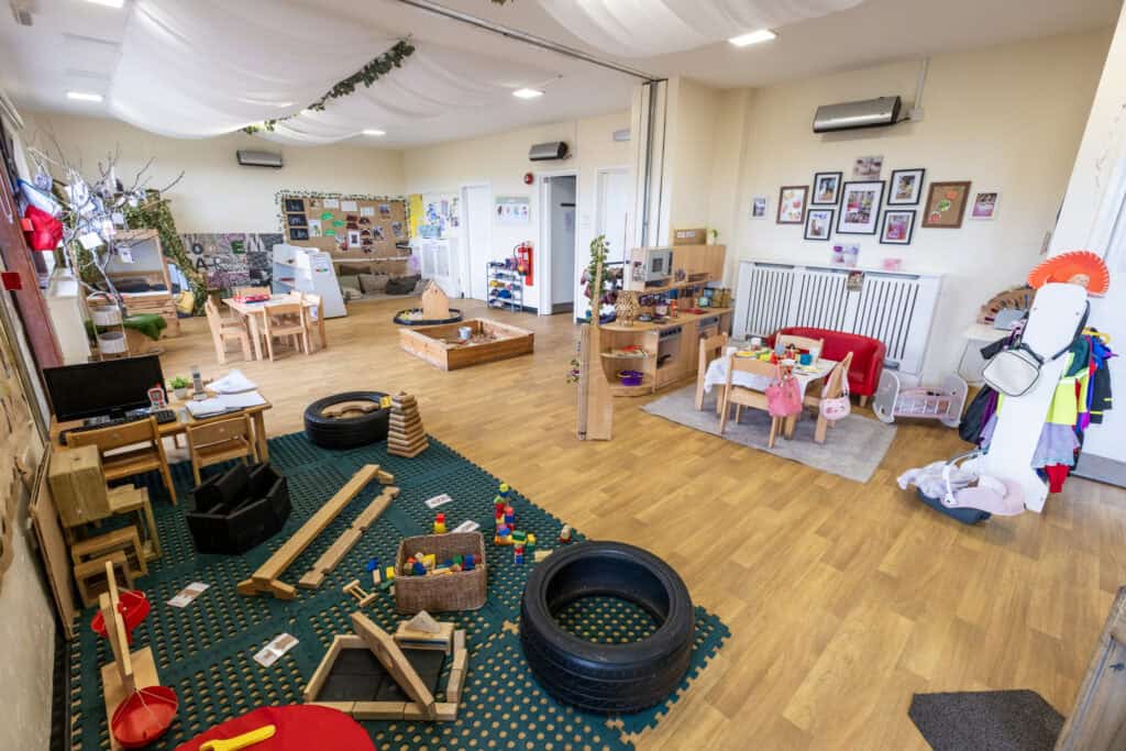 Bright, spacious indoor playroom at Thrive Childcare featuring soft seating, educational toys, arts and crafts area, and child-friendly furniture, perfect for early childhood development and nurturing learning environments.