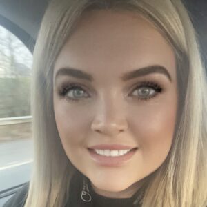 1. Bright smiling woman with striking blue eyes, blonde hair, and natural makeup, sitting in a car for a vibrant, welcoming image related to childcare and early education.