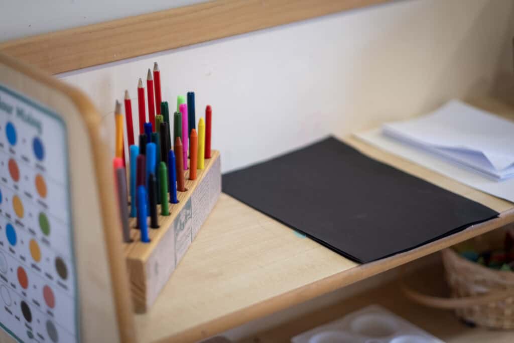 Colourful markers in a wooden holder at Thrive Childcare, fostering creative learning environments for children.