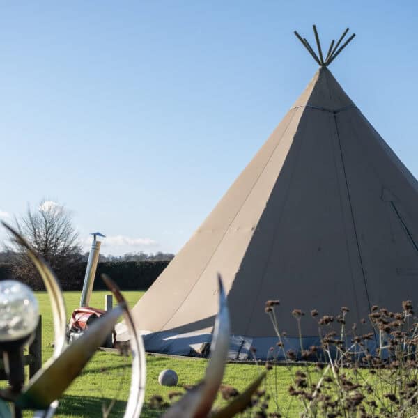 1. Colourful tipi tent outdoor play area at Thrive Childcare with green grass, blue sky, and nature background for children’s outdoor activities and early childhood development.