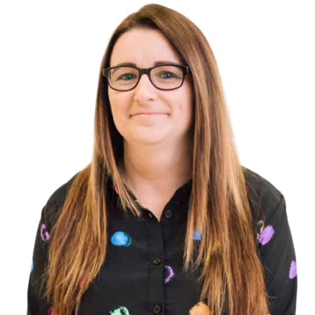Kindergarten teacher at Thrive Childcare smiling, wearing glasses and a colourful shirt, promoting a caring and engaging learning environment for young children.