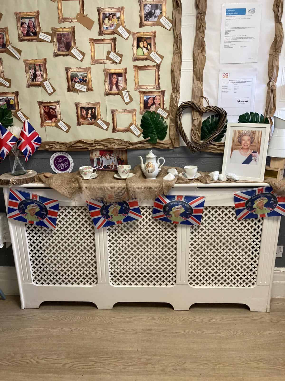A jaunty display celebrating Queen Elizabeth II with photographs, Union Jack flags, and memorabilia at Thrive Childcare, commemorating her reign and contributions in a colourful, patriotic tribute.