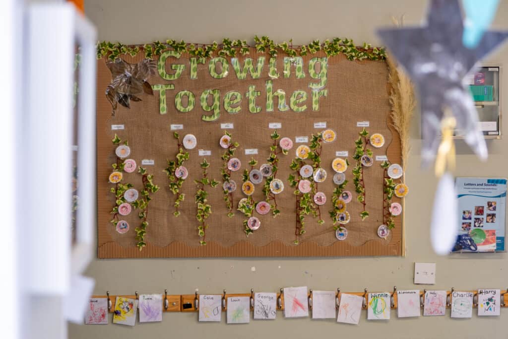 Growing together themed bulletin board with children's artwork and monthly displays at Thrive Childcare.