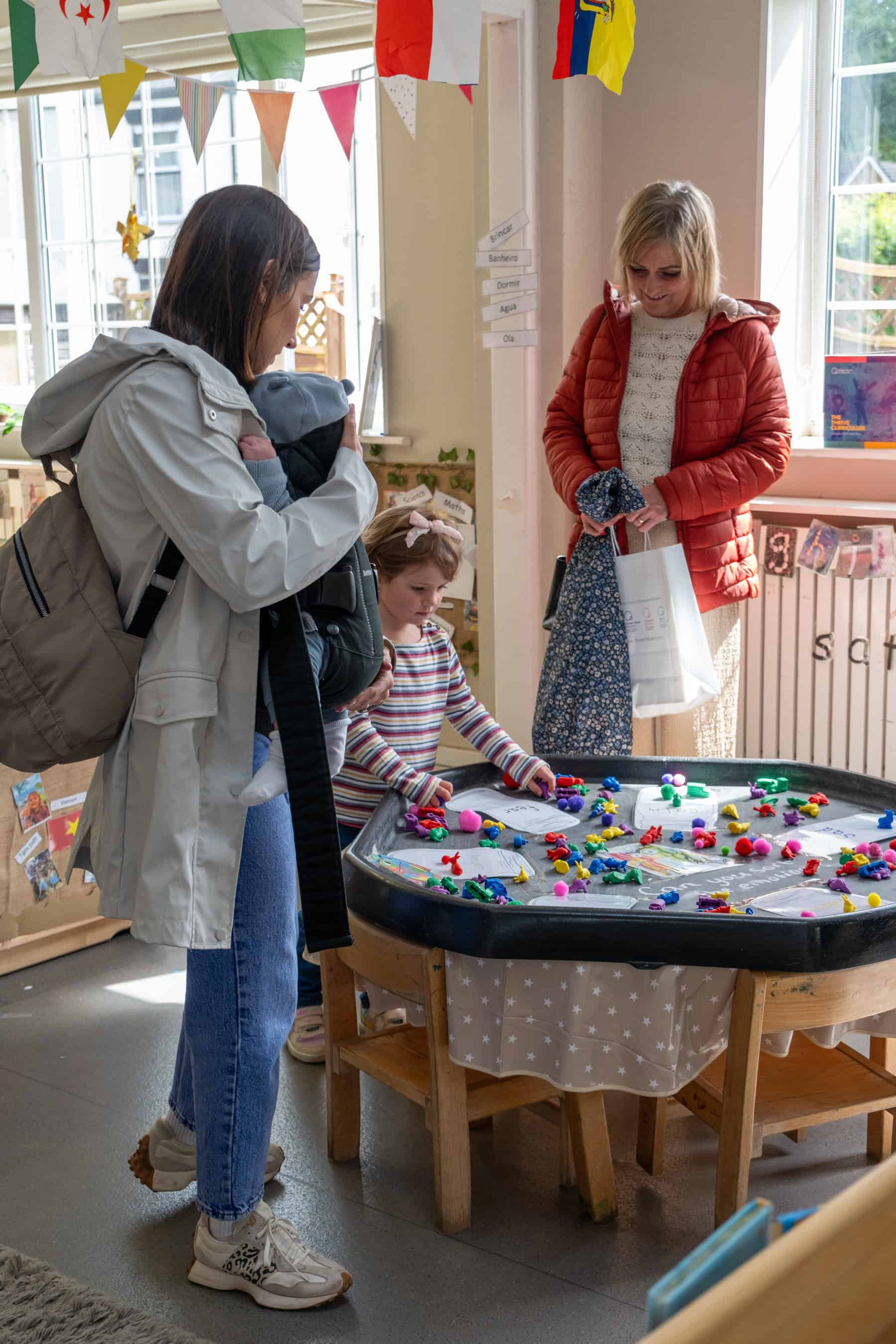 1. Happy children and parent at Thrive Childcare centre, engaging in educational activities and play in a bright, colourful classroom environment.