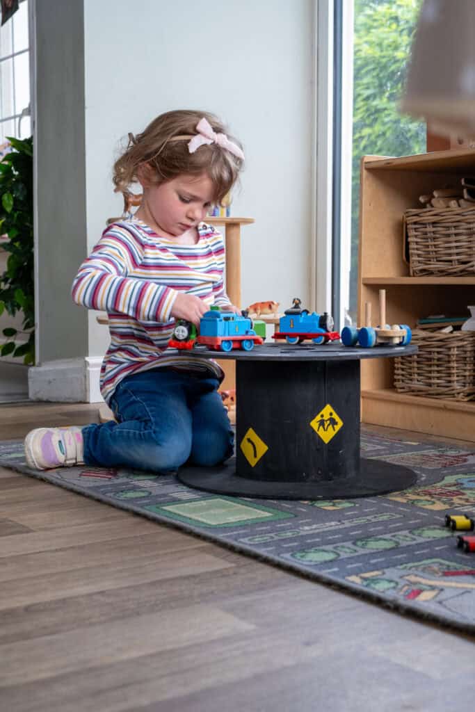 1. Young girl playing with Thomas the Tank Engine toys at Thrive Childcare centre, engaging in imaginative play with safe indoor toys for early childhood development.