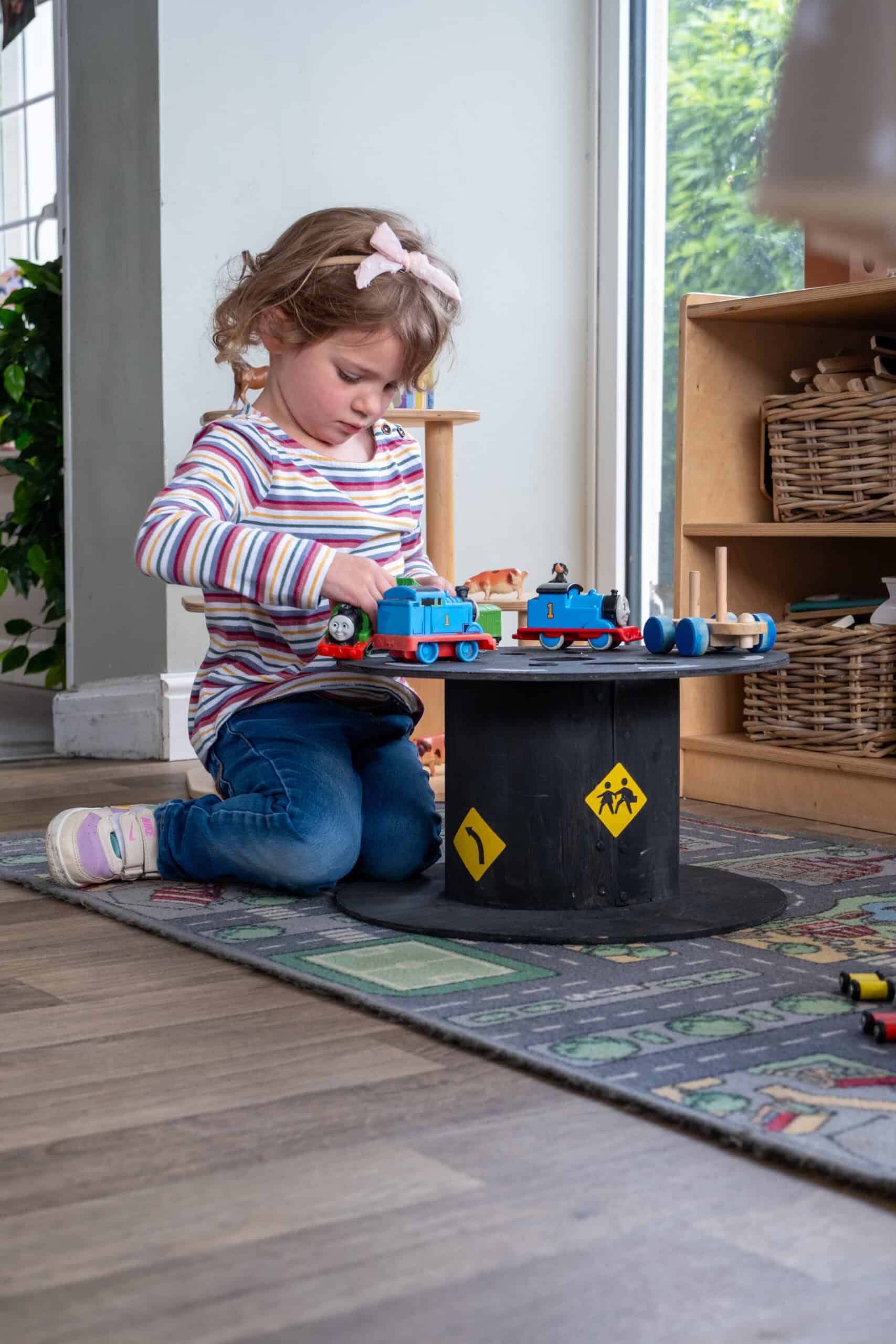 1. Young girl playing with Thomas the Tank Engine toys at Thrive Childcare centre, engaging in imaginative play with safe indoor toys for early childhood development.