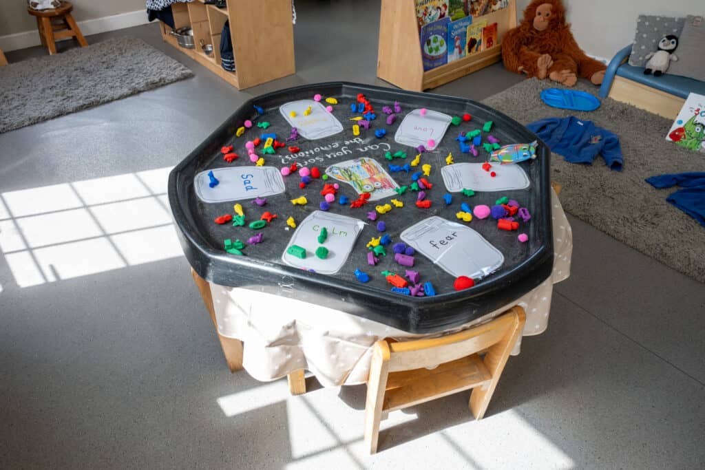 Brightly coloured sensory activity table in a childcare setting, encouraging early learning and development. Perfect for young children at Thrive Childcare, promoting creativity and sensory exploration.
