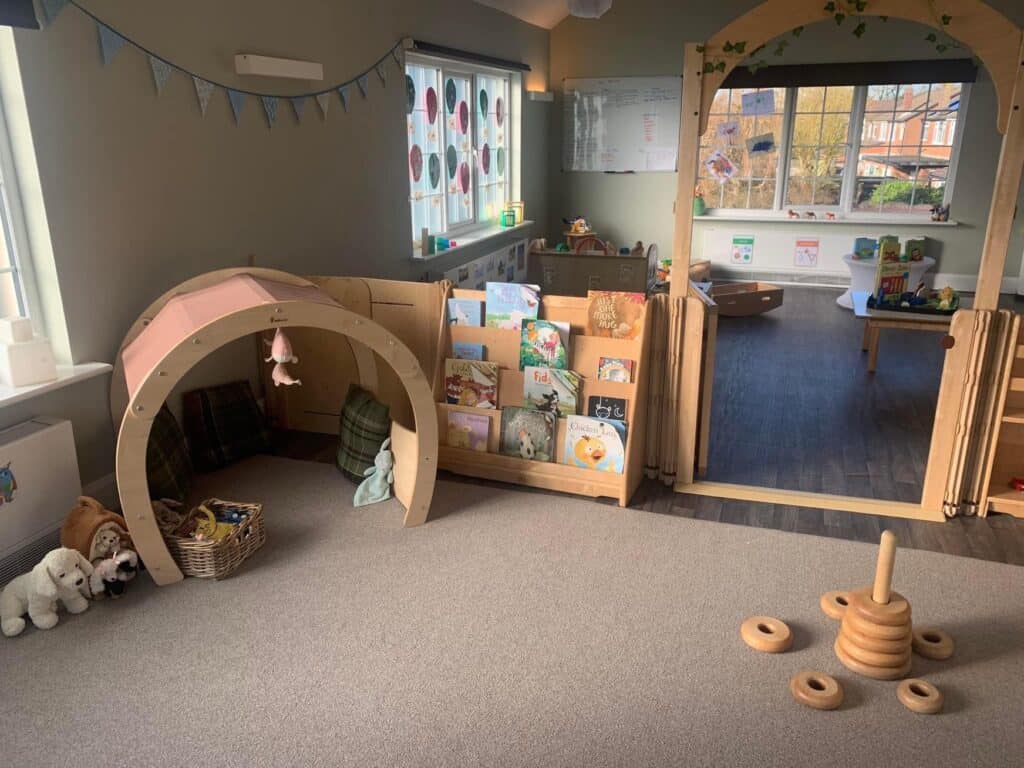 Bright indoor preschool reading and play area at Thrive Childcare, featuring cozy reading nook, toys, books, and soft furnishings designed to promote early childhood development and a nurturing learning environment.