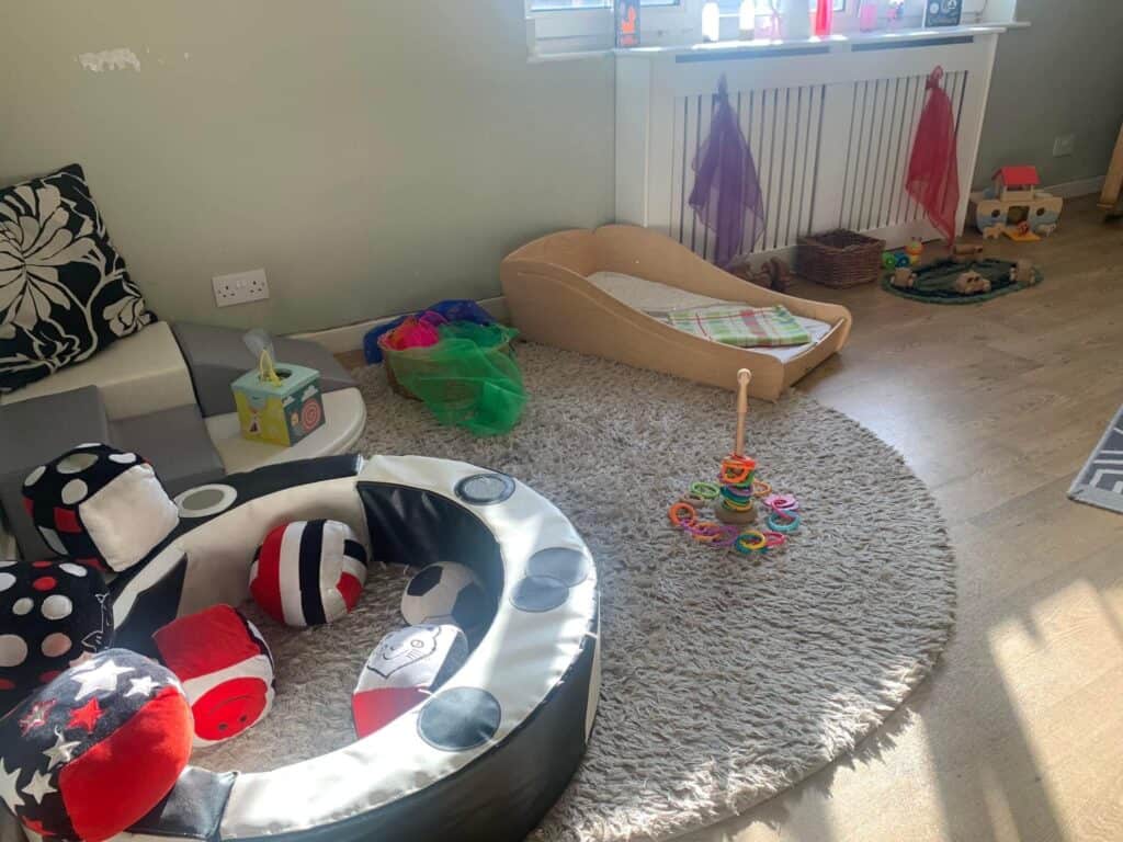 Bright, welcoming childcare playroom with soft carpet, toys, and a cozy bed for children, showcasing a safe environment at Thrive Childcare.
