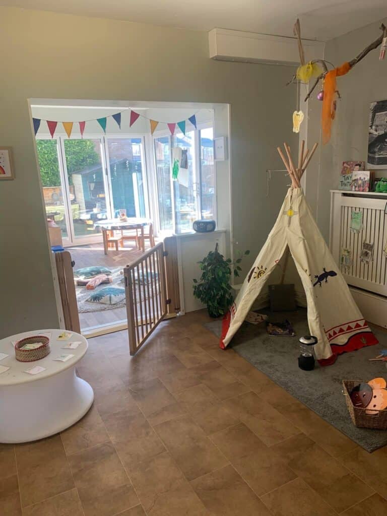 Bright indoor play area at Thrive Childcare, featuring a cosy teepee tent, colourful decorations, and a secure baby gate, designed for early childhood development and safe, fun nursery environments.