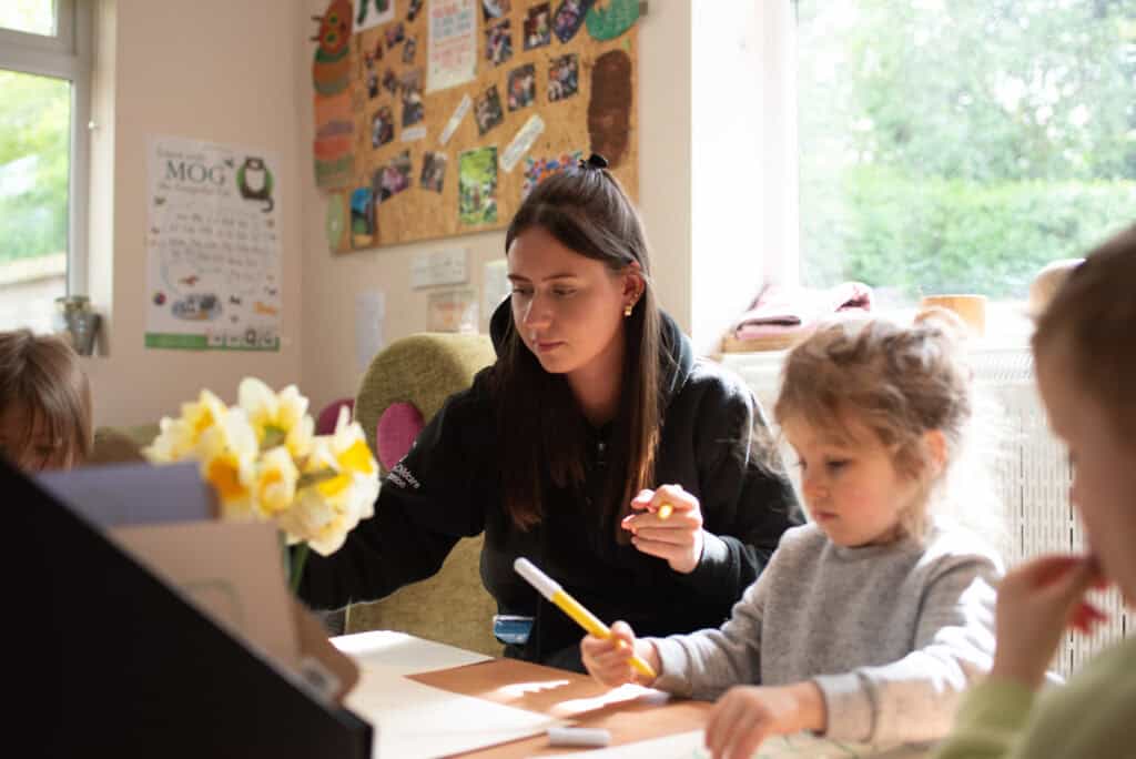 Thoughtful childcare educator engaging with young children in a bright, nurturing environment at Thrive Childcare centre. Focused on early years education, learning activities, and child development.