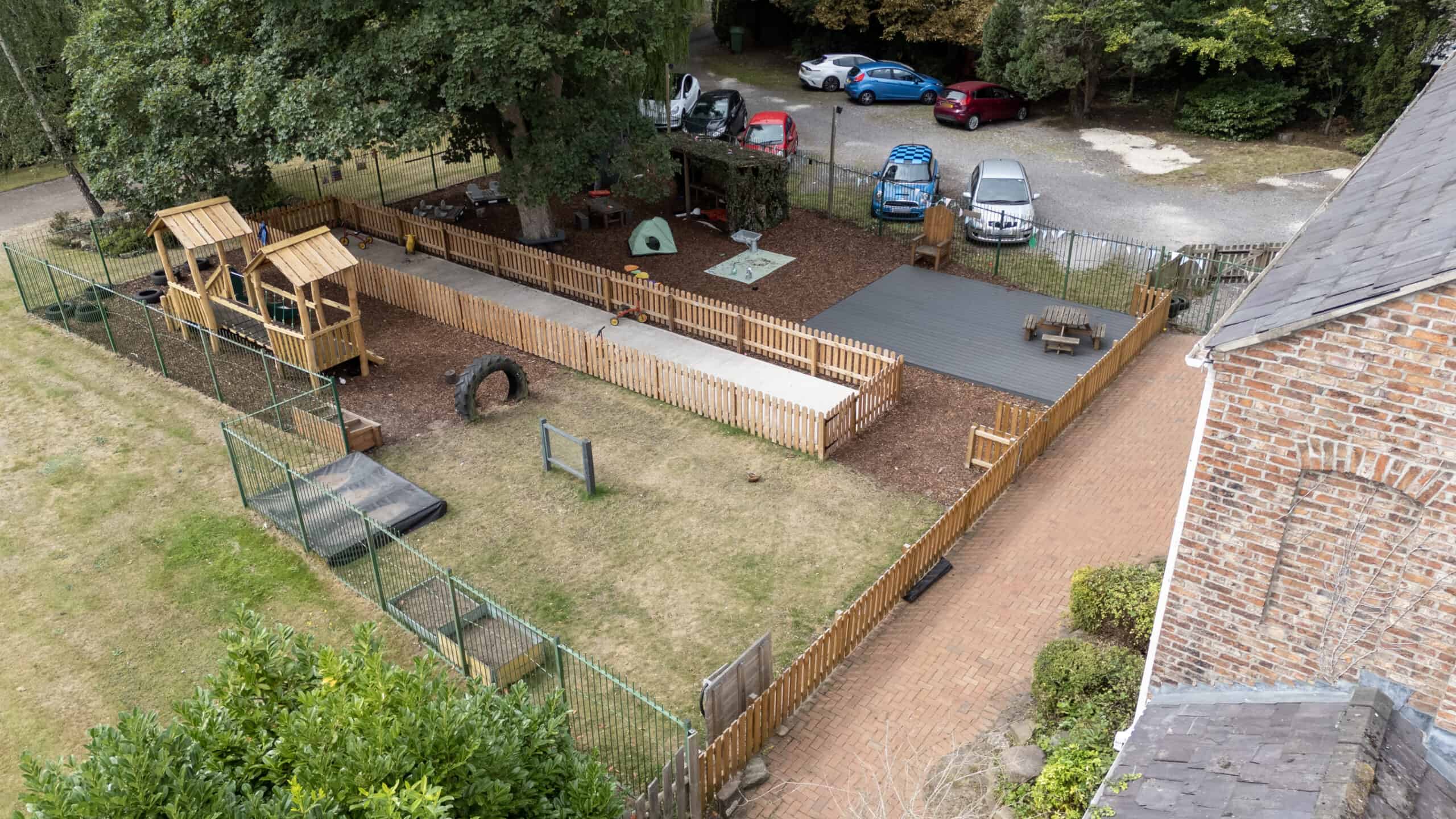 Bright and safe outdoor playground at Thrive Childcare with wooden play structures, artificial grass, and shaded areas, providing a fun and protective environment for children's activities.