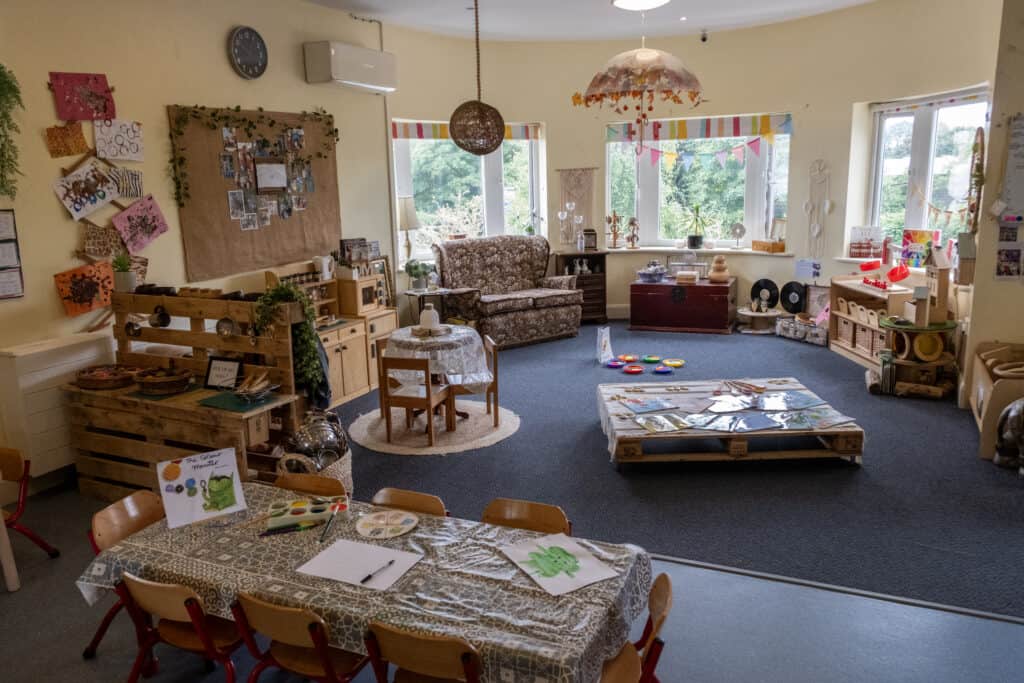 Bright, colourful indoor playroom at Thrive Childcare featuring toddler-friendly toys, arts and crafts, cosy seating, and natural light, creating a welcoming environment for young children's development and learning.