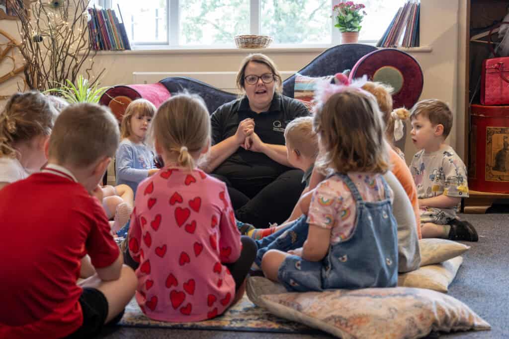 Bright childcare learning environment at Thrive Childcare with children engaging in story time with a caring educator, promoting early childhood development and play-based learning.