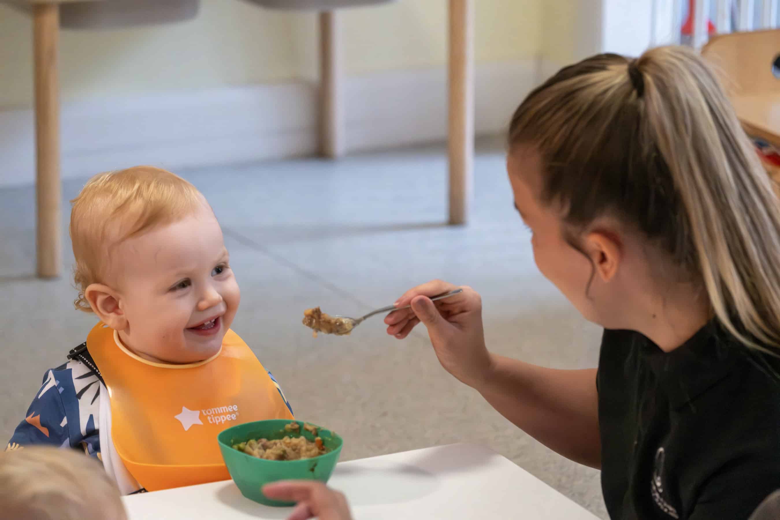 Bright toddler receives nutritious meal at Thrive Childcare, where caring staff promote healthy eating habits.